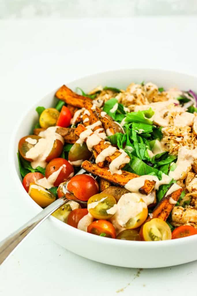 Salad bowls with sweet potatoes, chicken, and chipotle dressing.